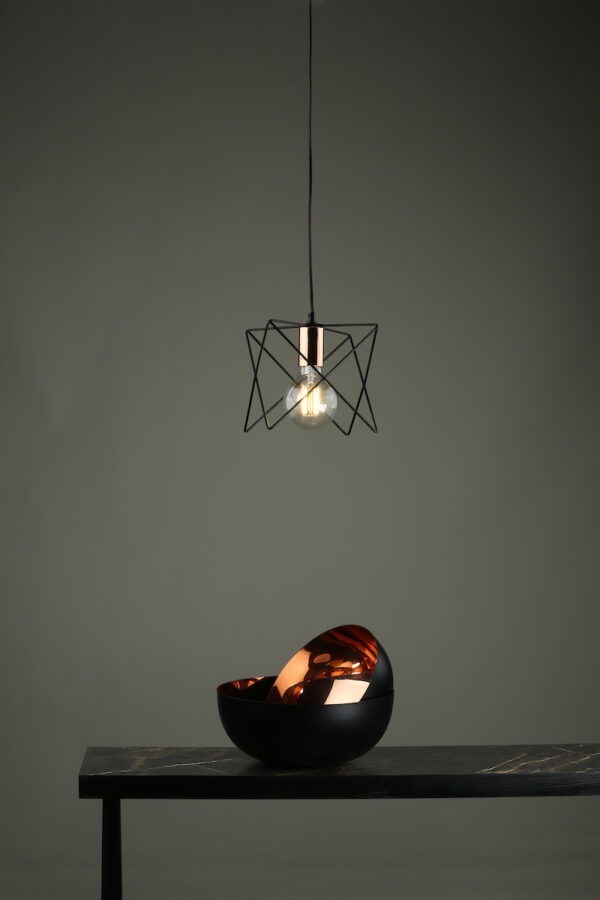 The midi 1lt pendant with black cage frame and polished copper lamp holder shown against a dark wall